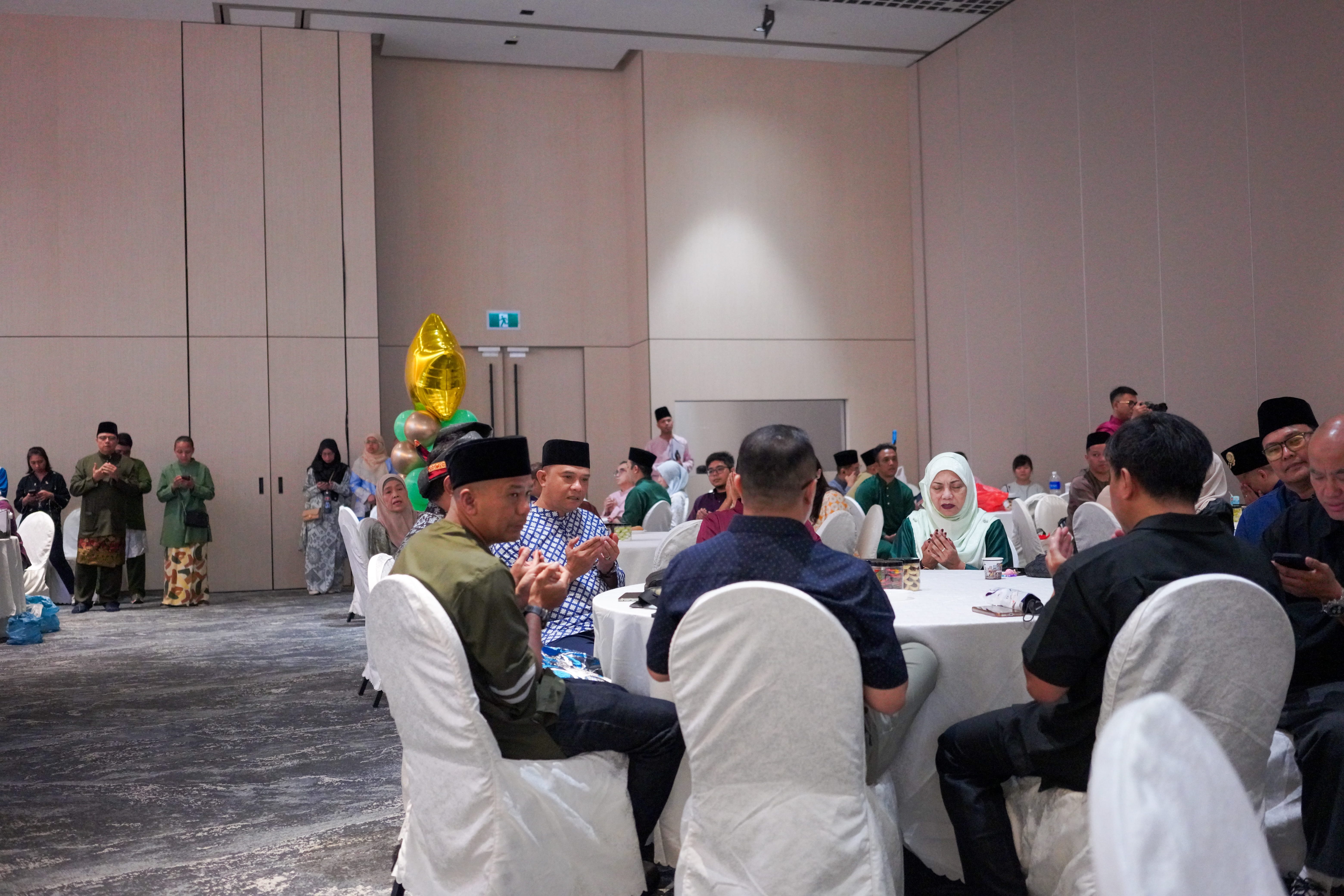 Guests seated at round tables during the opening prayer at the Annual General Meeting.